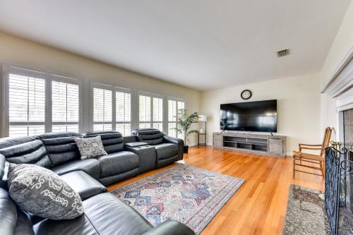 a living room with a black leather couch and a flat screen tv at Jacksonville Vacation Home with Trout River Access in Jacksonville