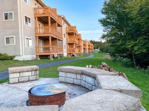 a row of apartment buildings with a fire pit in the yard at Remodeled Summit Condo at Snowshoe - Modern & Cozy in Snowshoe
