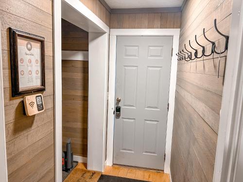 a hallway with a white door and wooden walls at Remodeled Summit Condo at Snowshoe - Modern & Cozy in Snowshoe