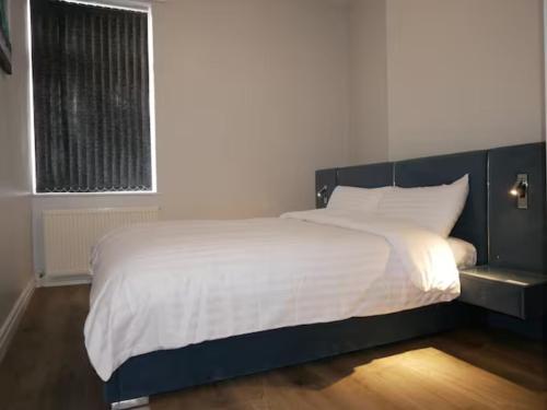 a bedroom with a large bed with white sheets and a window at Luxury Living Manchester in Manchester