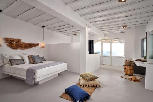 a white bedroom with a bed and a large window at Casa Tagoo Mykonos in Tagou