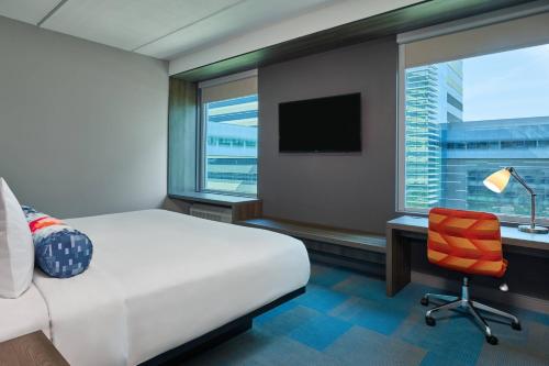 a hotel room with a bed and a desk and a window at Aloft Richardson in Richardson