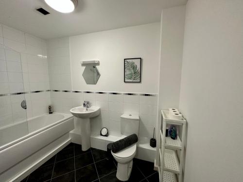 a white bathroom with a sink and a toilet and a tub at Etihad FC 2BR apartment with Water view in Manchester