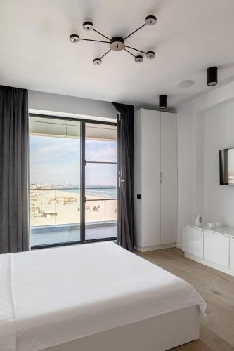a bedroom with a large white bed and a large window at Sea On Mamaia in Mamaia