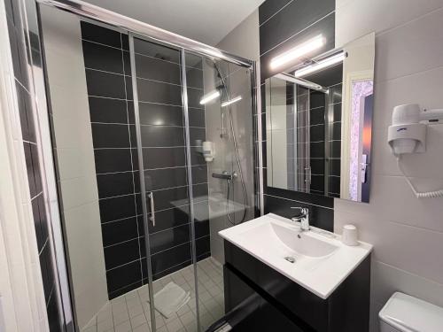 W łazience znajduje się umywalka i przeszklony prysznic. w obiekcie Hôtel Le Keroman w mieście Lorient