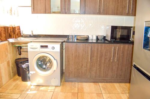 a kitchen with a washing machine in a kitchen at Fantastic location 1-Bed Apartment in Harare in Harare