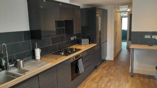 a large kitchen with a stove and a sink at The Newstead - 3 Bedroom Holiday Home in Weymouth