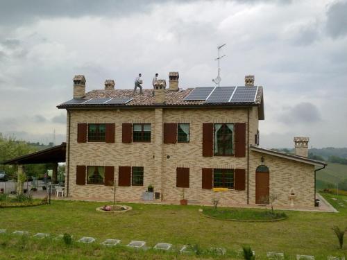 a man standing on the roof of a house with solar panels at Agriturismo bio Verde Armonia in Montemarciano
