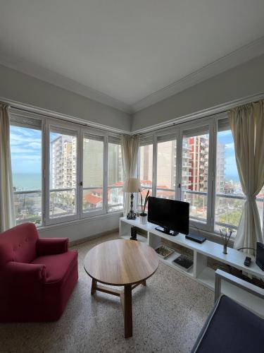 a living room with a couch and a table and windows at VENTANAS AL MAR in Mar del Plata