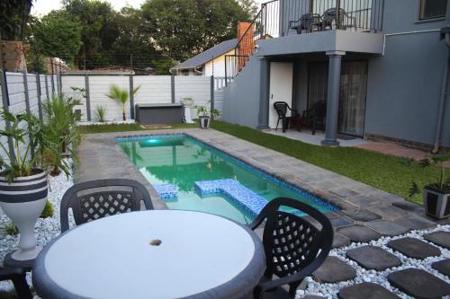 een tafel en stoelen naast een zwembad bij Villa La Sola B&B and Self-Catering in Boksburg