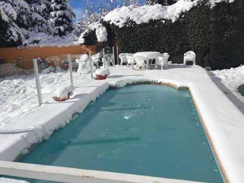 una piscina cubierta de nieve con sillas y mesas en HOTEL LE CHARME con parking en San Carlos de Bariloche