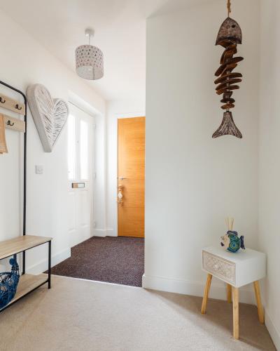 a hallway with white walls and a wooden door at Wee Jules By The Sea in Anstruther