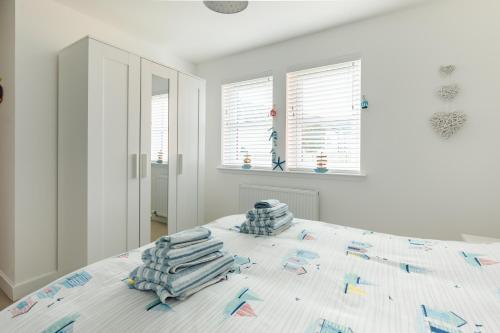a white bedroom with a bed with towels on it at Wee Jules By The Sea in Anstruther