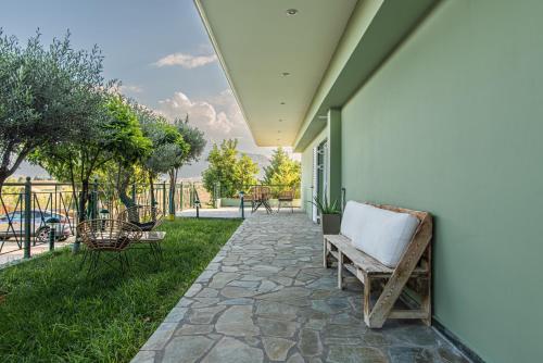 a patio with a bench and chairs on the side of a house at Masticha Apartment in Oinófita