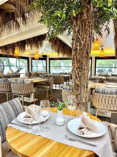 a dining room with tables and chairs and a tree at Hotel Majestic in Durrës
