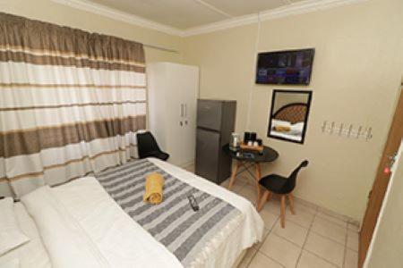 a bedroom with a bed and a desk in it at Quintax Guest House in Pretoria