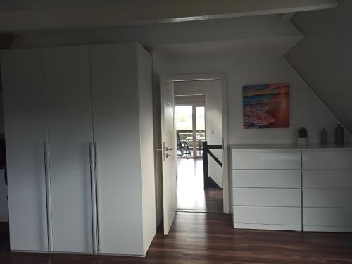 Habitación con armarios blancos y puerta a la cocina en Schöne Ferienwohnung mit Balkon auch für Handwerker und Monteure en Borsfleth