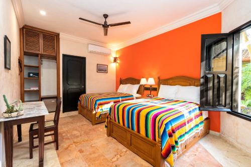 2 camas en una habitación con paredes de color naranja en Casa Clorinda, en Campeche