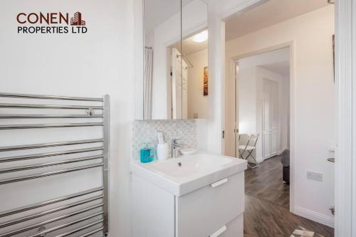 a white bathroom with a sink and a mirror at Captivating 2-Bed Apartment in Grays in West Thurrock