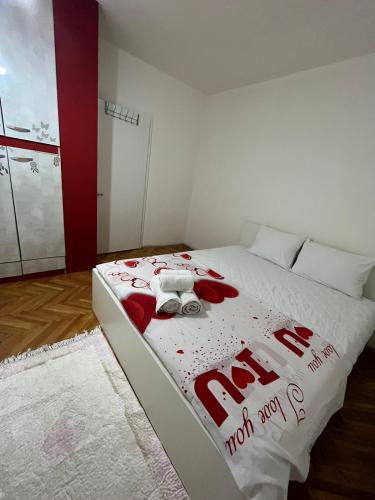a bed with a red and white comforter on it at Aleks 4 in Skopje