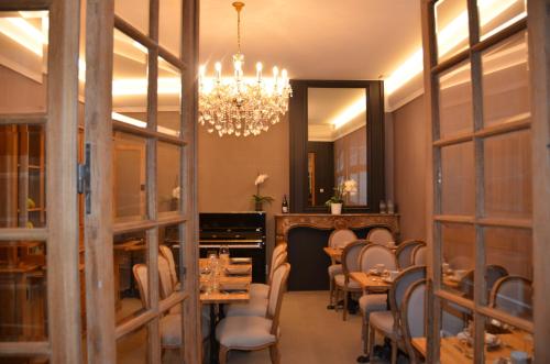a dining room with tables and chairs and a chandelier at Hotel Het Gheestelic Hof in Bruges