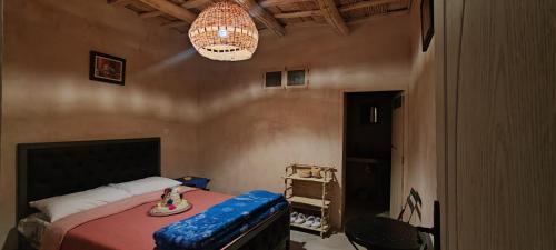 1 dormitorio con cama y lámpara de araña en Maroc des Merveilles - Chez L'habitant, en Kalaat MGouna