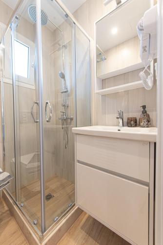 a white bathroom with a shower and a sink at Kanela Apartment - Hellenic Apartments Avlona in Oinófita