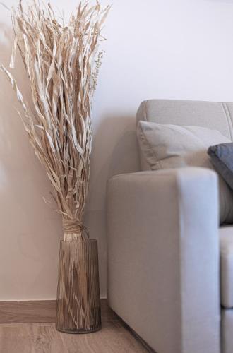 a vase with branches in it next to a couch at Kanela Apartment - Hellenic Apartments Avlona in Oinófita