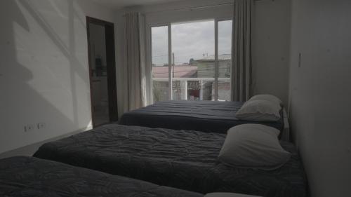 dwa łóżka w pokoju z oknem w obiekcie Hub House w mieście Kurytyba