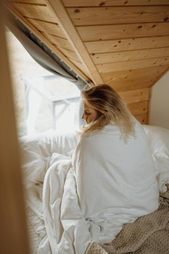 a woman sitting on a bed under a ceiling at Loft&Hill in Grywałd