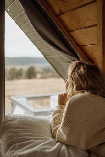 a woman sitting on a couch looking out a window at Loft&Hill in Grywałd