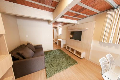 uma sala de estar com um sofá e uma televisão em Loft completo e aconchegante em Canela