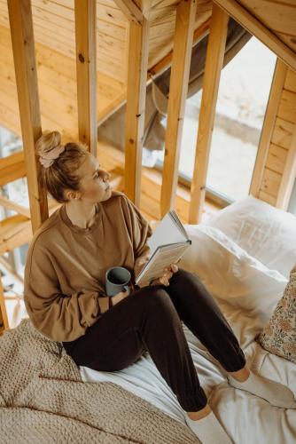 a woman sitting on a bed reading a book at Loft&Hill in Grywałd