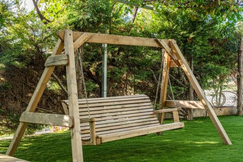 a wooden swing set sitting on a green lawn at Kanela Apartment - Hellenic Apartments Avlona in Oinófita