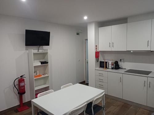 a kitchen with white cabinets and a white table at Casa Amado Fundão in Fundão