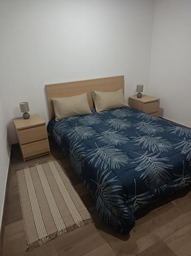 a bedroom with a blue comforter with two night stands at Casa Amado Fundão in Fundão