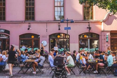 a group of people sitting at tables in front of a pink building at Spacious 2 rooms apartment in Helsinki Design District, own balcony in Helsinki