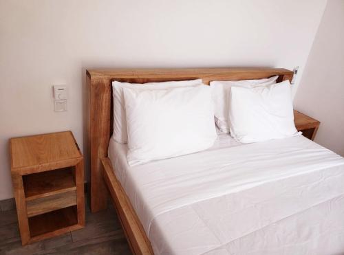 a bed with a wooden headboard and a night stand at Sipano Beach Lodge Kiwengwa in Kiwengwa