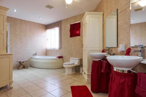 uma casa de banho com 2 lavatórios, uma banheira e um WC. em Aruba Palm Beach Villa em Palm-Eagle Beach