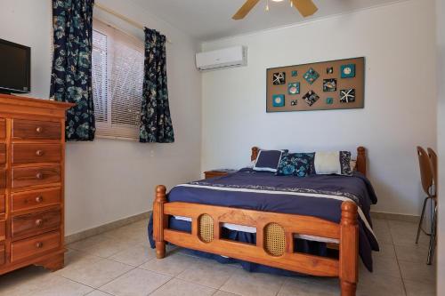 a bedroom with a wooden bed and a dresser at Aruba Palm Beach Villa in Palm-Eagle Beach