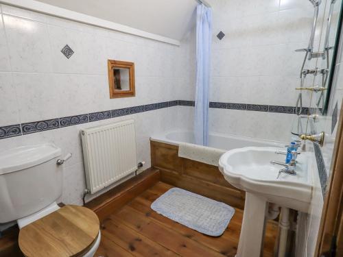 a bathroom with a toilet and a sink and a tub at Tithe Cottage in Cockermouth
