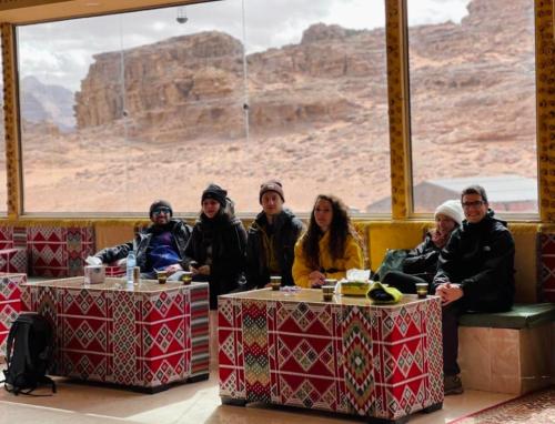 a group of people sitting at tables with a view at sand magic camp in Wadi Rum