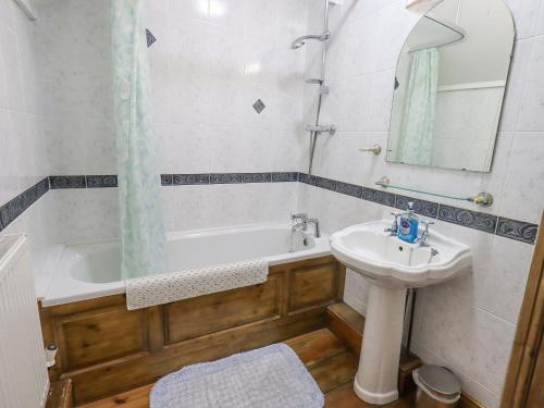 een badkamer met een bad, een wastafel en een spiegel bij The Byre in Cockermouth
