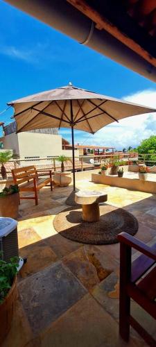 un patio con mesa y sombrilla en Deu Praia Pousada en Jericoacoara