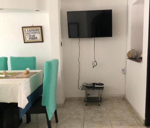 a dining room with a table and a tv on the wall at Casa prado alto in Barranquilla