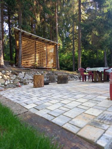a stone patio with a log cabin in the woods at Chatka v lese in Ružomberok