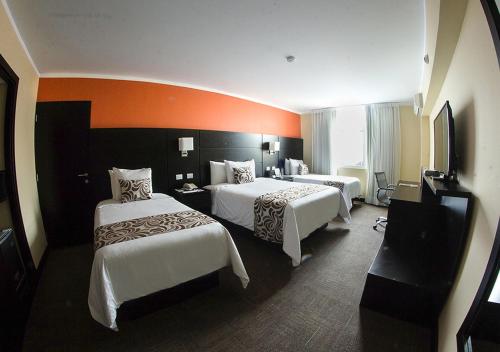 a hotel room with two beds and an orange wall at Hotel El Gran Marqués in Trujillo