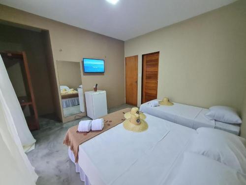een kamer met 2 bedden, handdoeken en een televisie bij Deu Praia Pousada in Jericoacoara