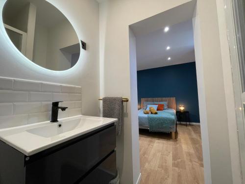 ein Badezimmer mit einem Waschbecken und ein Schlafzimmer mit einem Bett in der Unterkunft Le Magnifique Spacieux - 6 personnes - 3 chambres avec SDB privatives - idéal entreprise in Lens