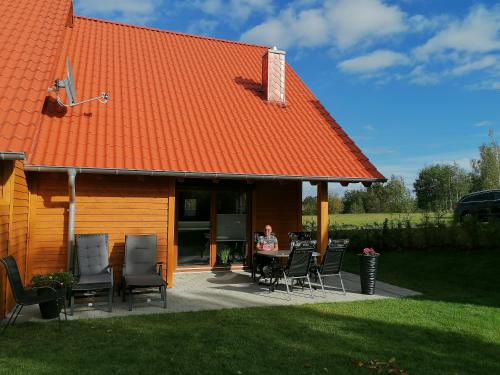 a woman sitting at a table in front of a house at Premium-Plus-Ferienhaus Havanna Select in Hasselfelde